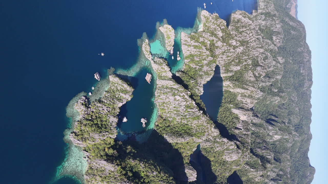 Drone view of Philippines, Coron Island’s untouched coastline, surrounded by lush forests and clear waters. Aerial view of bungalows and lagoon. Wide rotating shot. Vertical video.