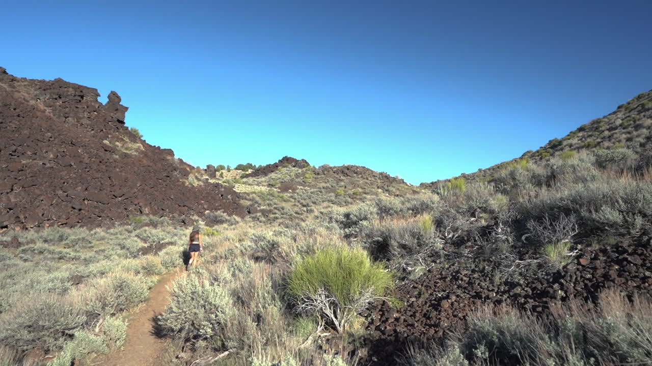 mujer solitaria caminando por el camino del desierto en un día soleado