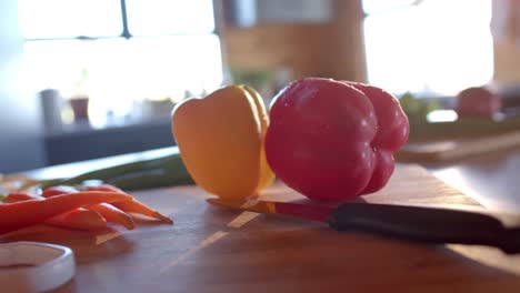 organic vegetables and knife on countertop in sunny kitchen, slow motion