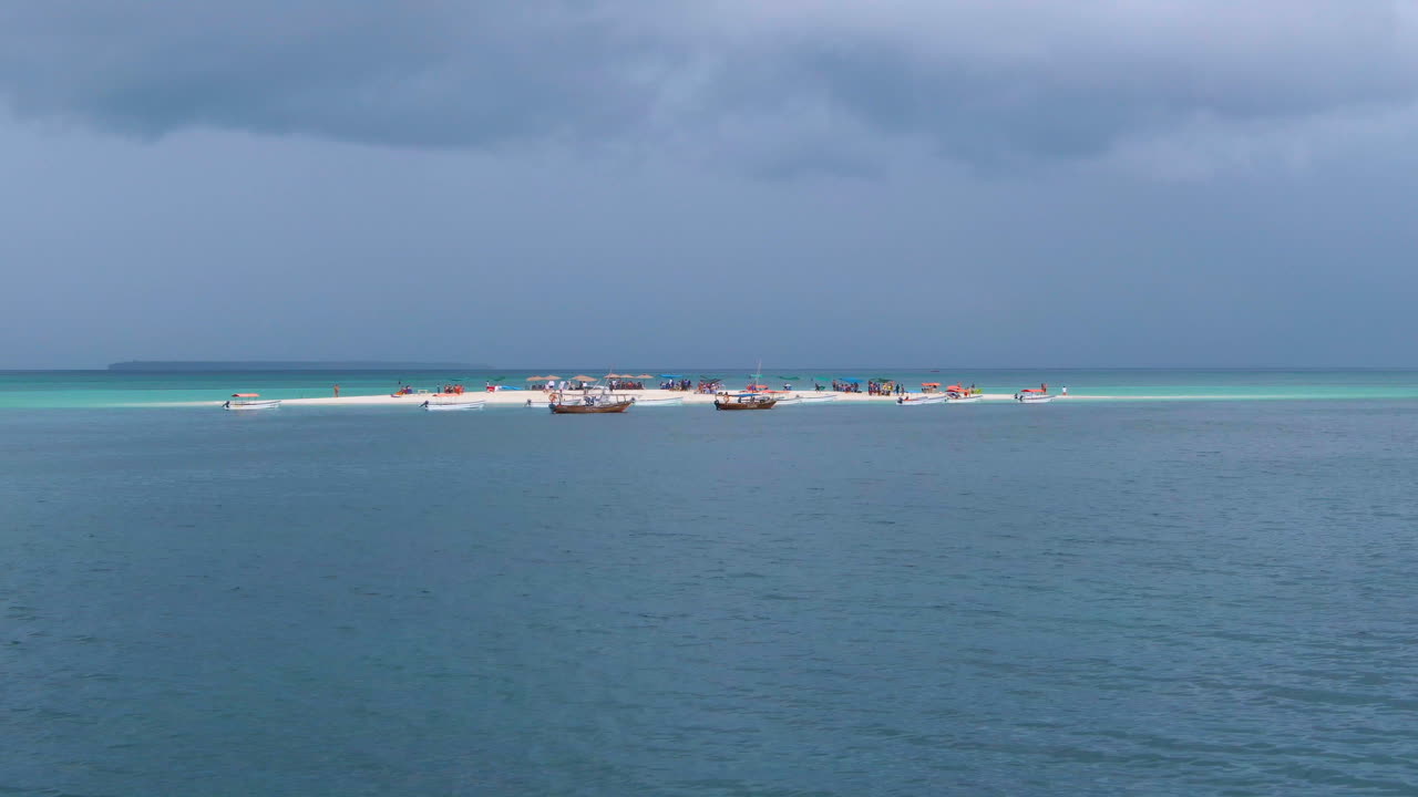 사람과 보트로 가득한 열대 모래 섬의 물 위에서 무인 항공기 보기