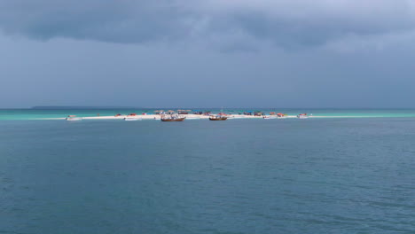vista de drones sobre el agua de la isla de arena tropical llena de gente y botes