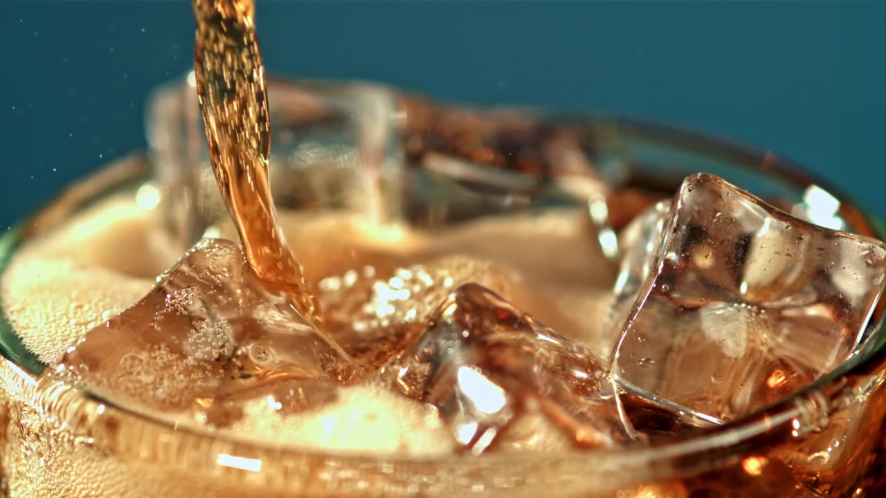 Cola rinfrescante versata su cubetti di ghiaccio al rallentatore