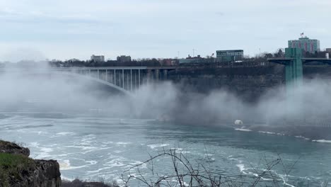 rainbow bridge in niagara falls - united states and canada border bridge over niagara river close up telephoto as mist from waterfall passes - zoomed bridge going to usa and canada national border