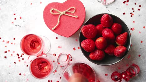 Bottle-of-rose-champagne--glasses-with-fresh-strawberries-and-heart-shaped-gift