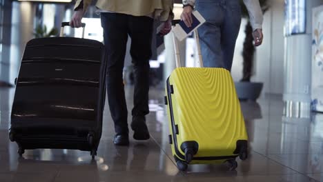 un par de viajeros llevan su equipaje y pasaportes. caminando por la sala de espera de la terminal, vista de atrás. la gente se está preparando para