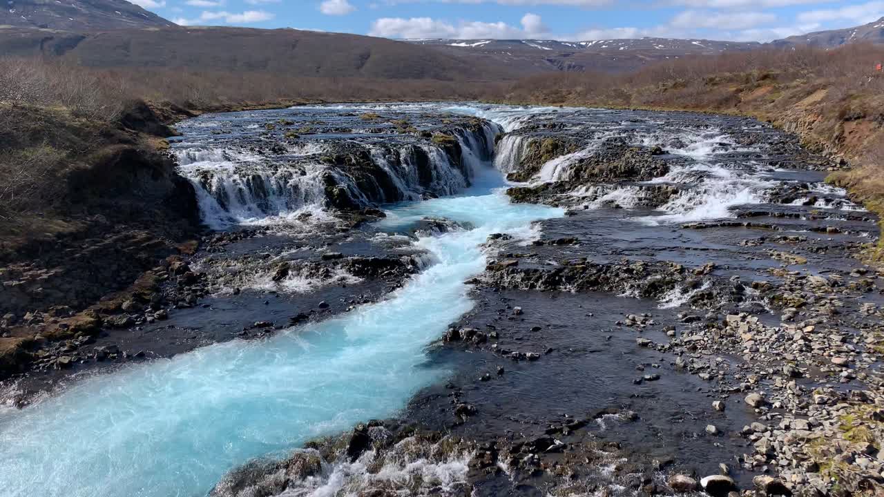 View over the beautiful waterfall Bruarfoss with Icelands most turquoise water, watching the water pouring from the rocks down in a stream and whirling around