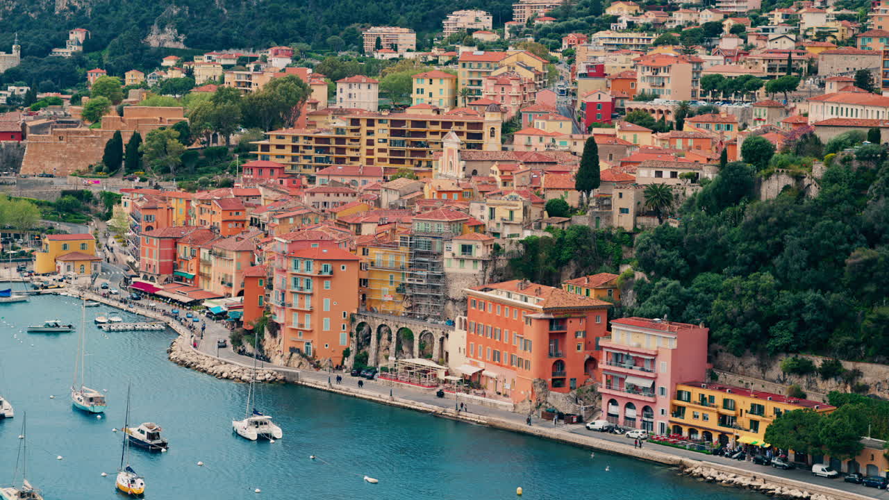 View of the colourful buildings of Villefranche sur Mer, France on the coast with small boats docked on the sea