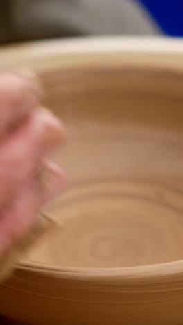 manos moldeando arcilla en una rueda de cerámica