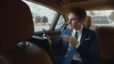 Serious-business-man-having-video-chat-on-mobile-phone-in-modern-car.