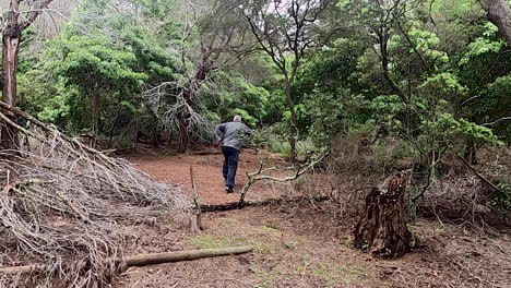 plano general de un hombre caucásico huyendo a través del arbusto del bosque