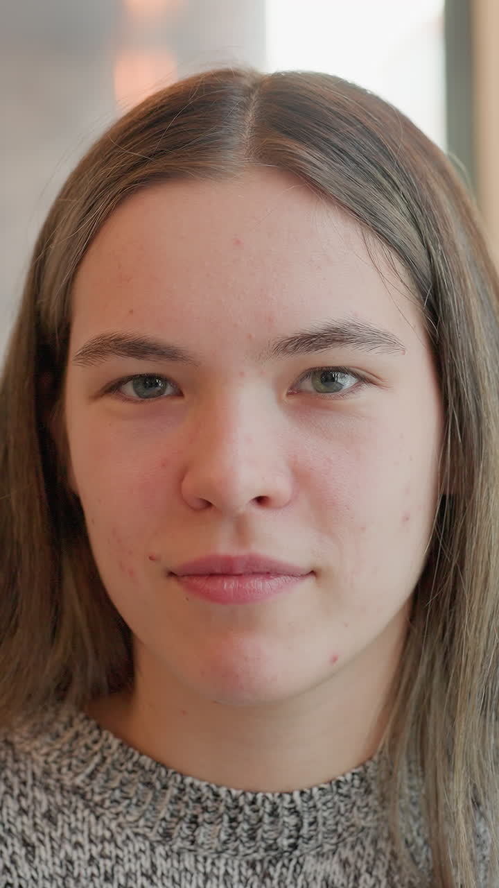 Primer plano de una mujer blanca mostrando expresiones sutiles, suéter cómodo y luz de ventana, serie de microexpresiones desde una sonrisa hasta el ceño fruncido y una mirada pensativa, la secuencia del retrato sugiere una estudiante