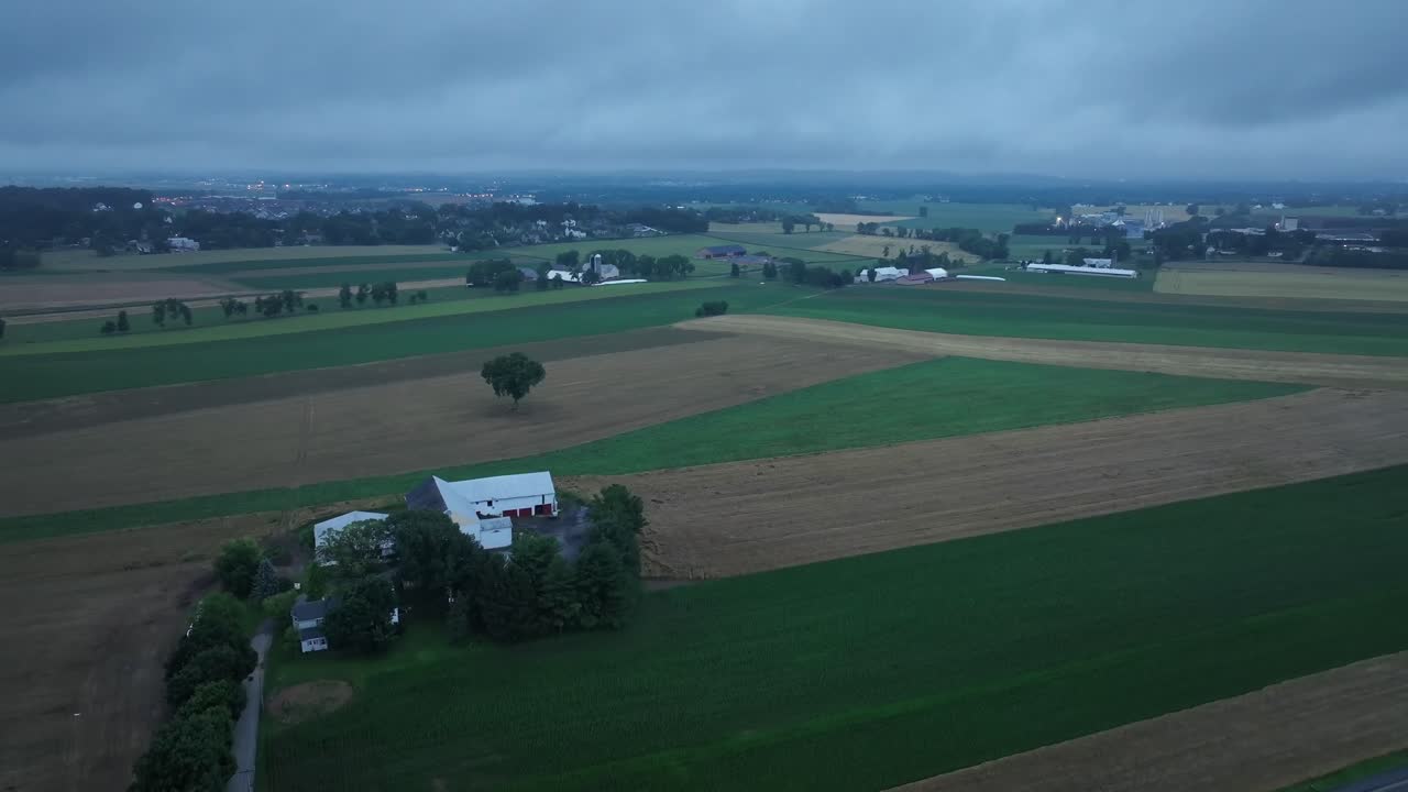 Mørke skyer over landbrugsmarker og en amerikansk gård. Dramatisk himmel om aftenen. Vidvinkeloptagelse fra drone, der daler ned. Dyrkede marker og plantage.