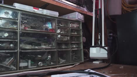 hombre agarrando hardware de un contenedor de almacenamiento de tuercas y tornillos dentro de un garaje