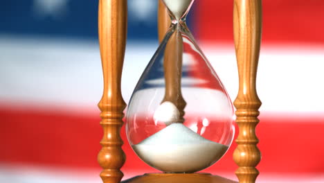 sand flowing through hourglass with american flag background