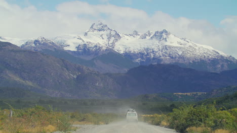 a white van drives down a gravel road head toward a mountain range