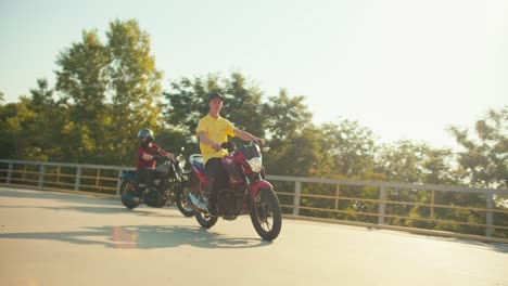 review on training a motorcyclist in a motorcycle school. the guy instructor in a yellow t-shirt rides on a training ground in a motorcycle school in sunny weather