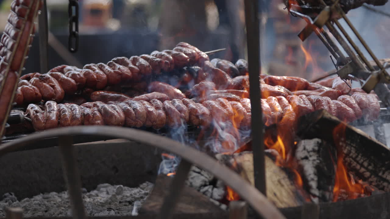 Grilled sausage argentine barbecue with burning and smoking firewood, close up