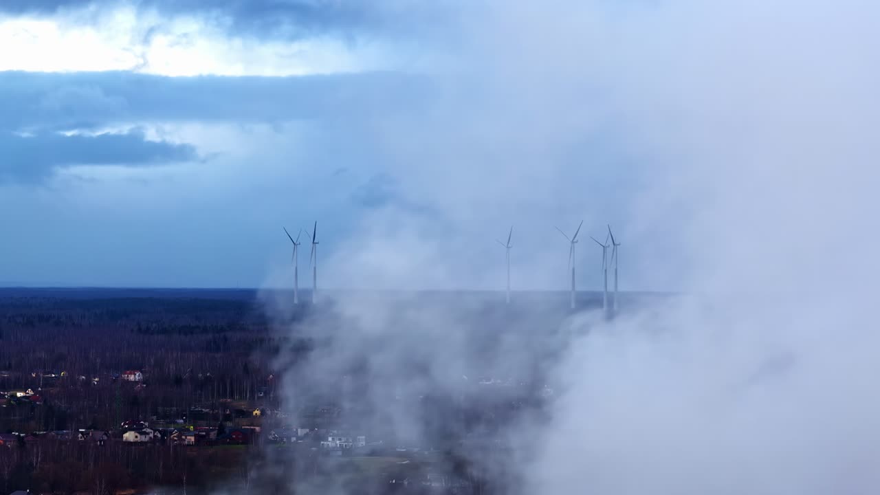 Un dron sigue el rastro que dejó el humo a la deriva para revelar un campo de aerogeneradores, enfatizando el cambio hacia la energía renovable