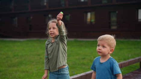 girl launches flying toy with brother on deck near hotel