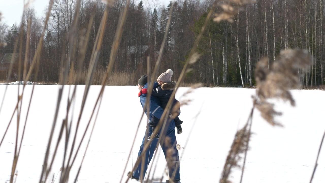 Il nonno porta la bambina sulla schiena in un paesaggio invernale bianco, slow motion.