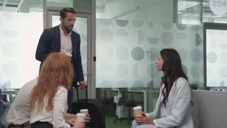 a working group of two businesswomen and two businessmen chatting relaxedly with some coffees in the lobby of an airport before a business trip 6