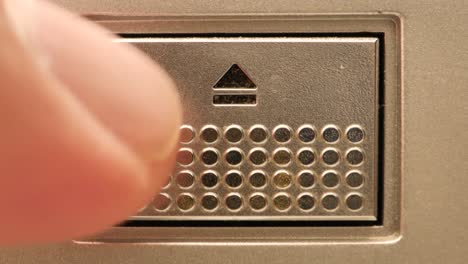 extreme close up of an eject button a finger pushes it and then pushes the button aggressively