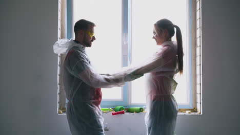 positive-family-in-transparent-coveralls-dances-near-window