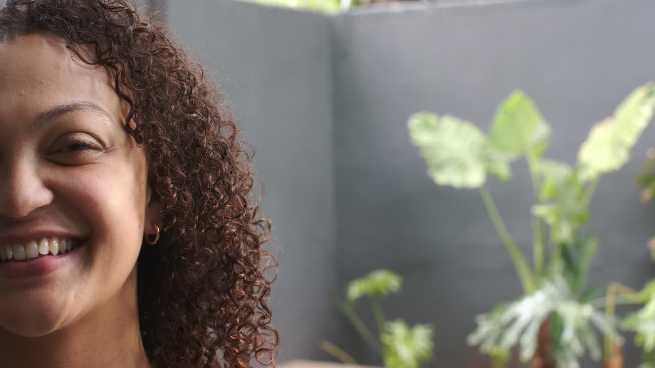 Mulher afro-americana reagindo a sinal de áudio, sorrindo e rindo em pátio perto de plantas, espaço para texto