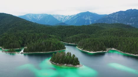 una hermosa vista aérea de un lago turquesa, bordeado por un vasto bosque de árboles, y una majestuosa montaña en el fondo