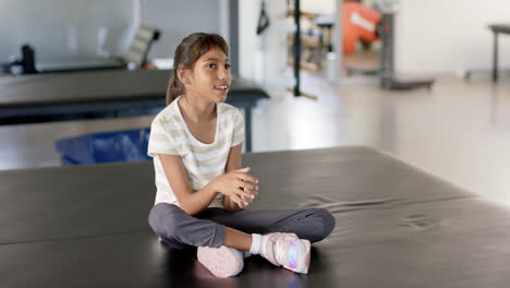 smiling during disability rehabilitation session, girl with cerebral palsy sitting on therapy table