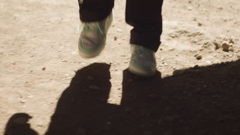 guy with white shoes walking in the dusty dessert in the hot sun