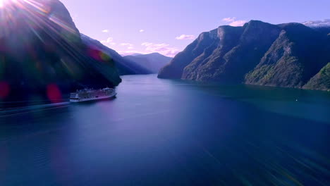 Aerial-View-Of-Cruise-Ship-Sailing-Through-Dreamy-Fjord-With-Sun-Flares-Hitting-Lens