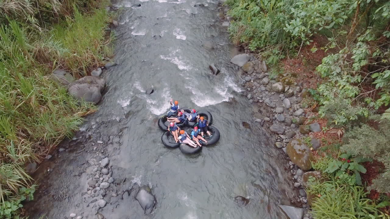 Orang-orang bersenang-senang melakukan tubing di sungai Mindo dengan perlengkapan keselamatan.
