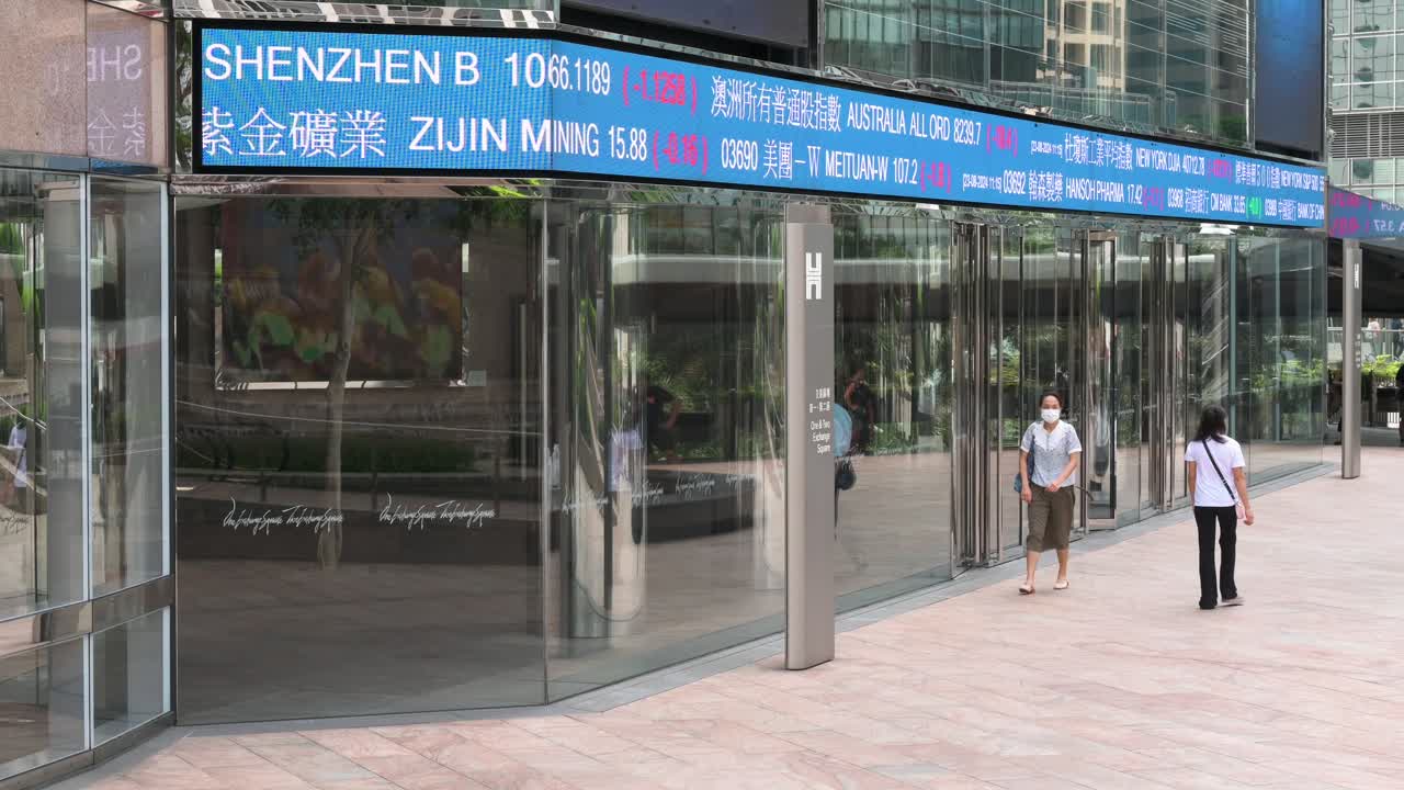 A moving screen displaying negative stock ticker symbols catches the attention of passersby at Exchange Square, the site of the Hong Kong Stock Exchange (HKEX) in Hong Kong's financial district.