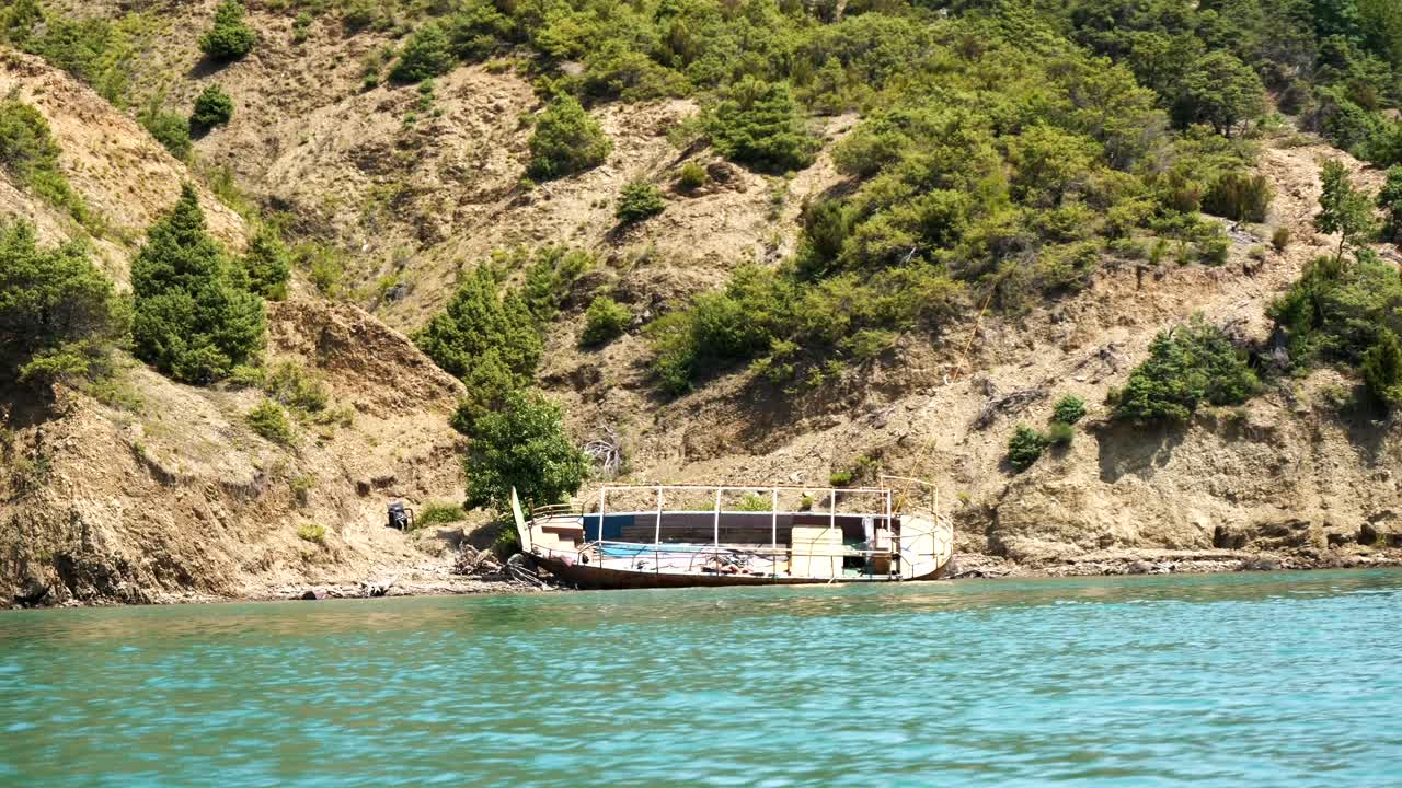 Albania, Lake Koman, view from a ferry of the lake shore and the wreck of a broken boat