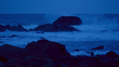 ocean waves crashing onto rocky north atlantic shore at cloudy hazy autumn dusk. lofoten islands, northern norway.slow motion 120fps.