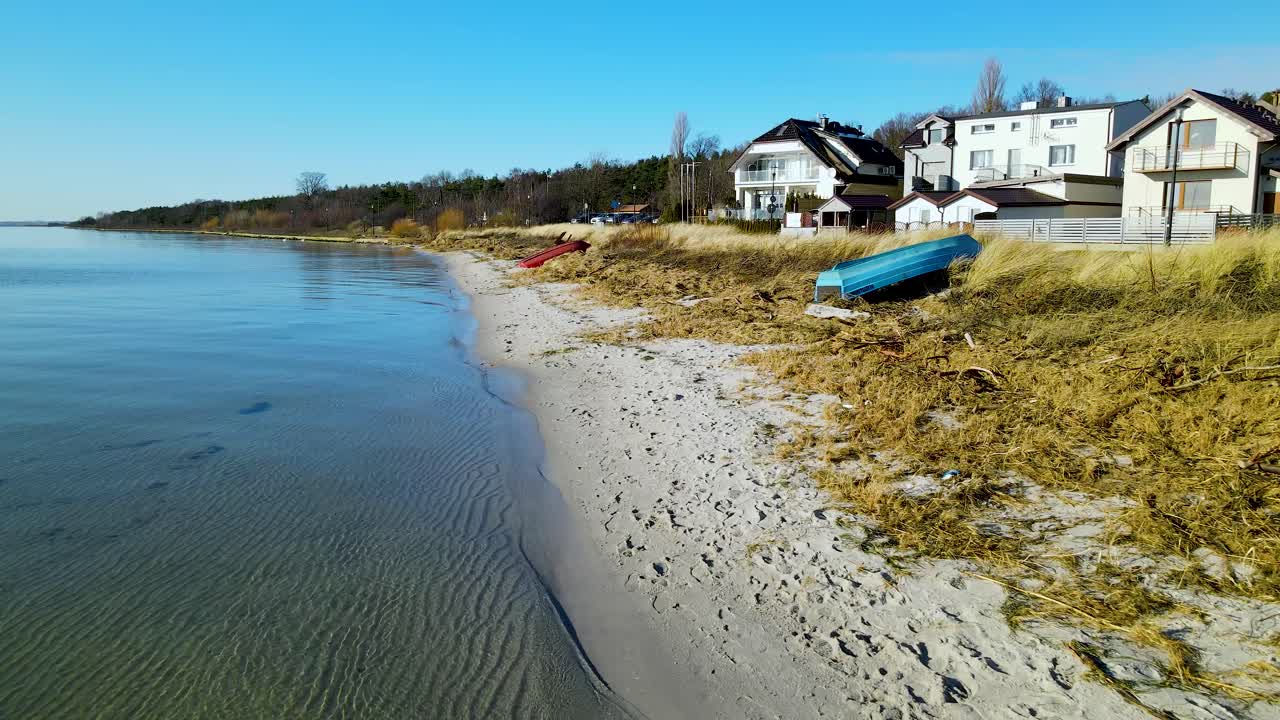 폴란드의 맑은 여름날 아름다운 전망을 감상할 수 있는 거대한 고급 빌라가 있는 작은 모래 해변에 있는 맑고 푸른 호수에서 조용히 잔물결을 일으키는 물