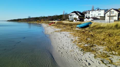 calmly rippling water from the clear blue lake on a small sandy beach with huge luxury villas with beautiful views on a clear summer day in poland
