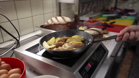 Frying-And-Pan-flipping-Potatoes-Over-Induction-Cooker-In-The-Kitchen---close-up,-slow-motion