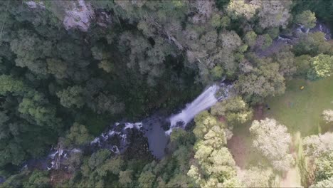 Blick-Aus-Der-Vogelperspektive-Auf-Einen-Atemberaubenden-Wasserfall,-Der-In-Einen-Bach-Stürzt,-Der-Durch-Einen-Dschungel-Fließt