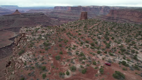 aerial view of red suv vehicle moving on desert dirt road to stunning viewpoint of utah desert, marlboro point, moad usa