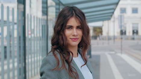 a young woman smiling at the camera at a bus stop
