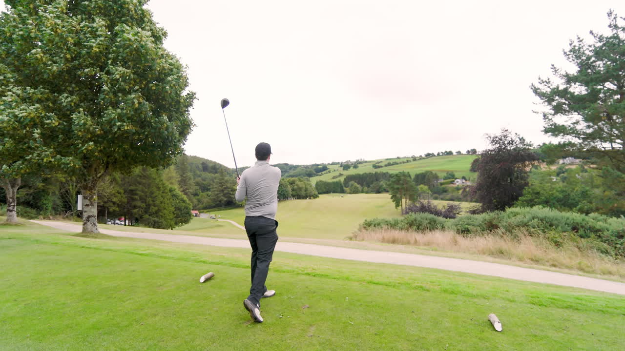 Male golf player playing golf, hitting the ball with club on a golf course, copy space