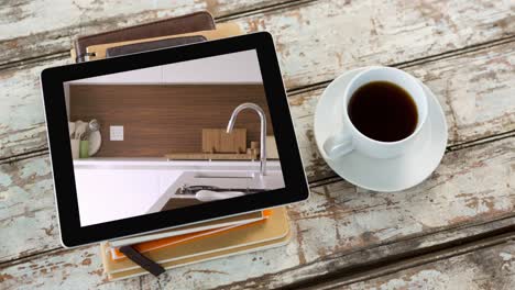 digital tablet with modern kitchen interiors displayed on screen on wooden surface