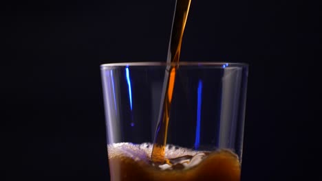 a pint glass being filled with ice cold coffee