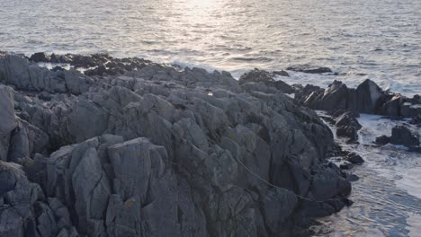 rocky cape with sun reflected ocean at sunset golden hour