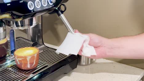 a person cleans and operates an espresso machine, preparing a coffee in a cozy kitchen setting with warm lighting