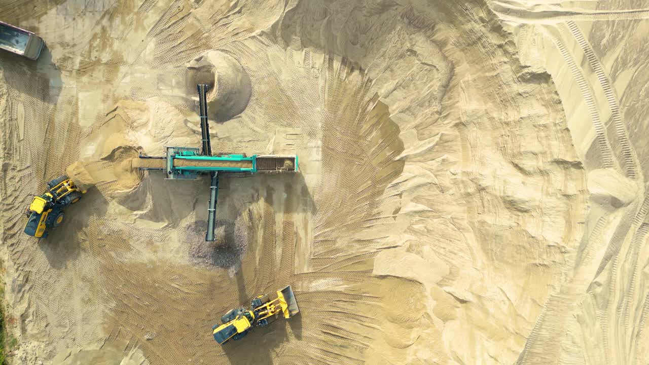 Wheel loader with bucket in front load stone in crusher, aerial drone shot