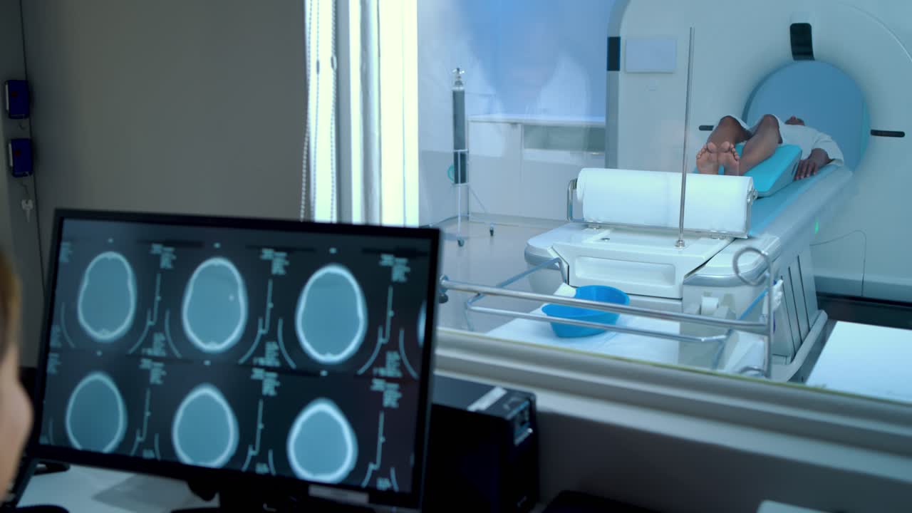 Lo scanner si avvia, aggiornando il monitor mentre il tecnico controlla le sezioni nella sala di controllo per chiarezza