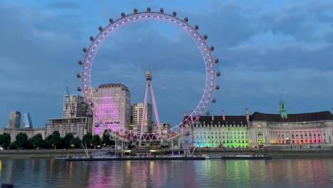 london eye illuminated at dusk, reflecting vibrant colors on the calm river thames